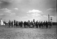 [Large group of Indian men & one child and one cowboy (possibly Ricker) on horseback all in arena]