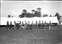 [Group shot of sixteen Cowboys and Cowgirls in front of tent]