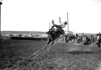 [Manuel Enos leaning back in saddle attempts to maintain his ride as he falls to the side of bronc]