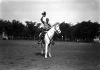 [Col. Jim Eskew waving hat in air on white horse with silver mounted tack]