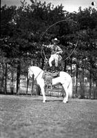 [Possibly Junior Eskew standing on horse spinning a vertical rope loop in front of himself]