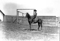 [Unidentified Cowboy with rope on saddle in front of corral]