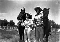 [Possibly Juanita and Weaver Gray in satin shirt and hat; he in pin-striped pants holding horses]