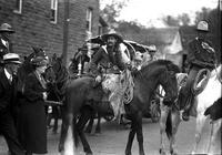 [Pistol Pete Eaton with waist-length hair, colt in holster, and wooly chaps atop horse]