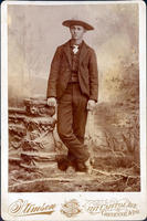 Man posing in suit, cowboy hat and boots