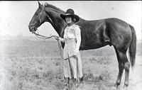 Bonnie McCarroll standing beside unsaddled horse