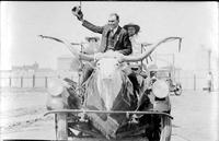 [Ralph R. Doubleday riding on a mounted steer head on an automobile]