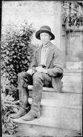 Boy wearing hat and high boots sitting on steps outdoors