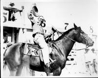 [Cowboy, probably Leonard Stroud, on horseback tipping hat to camera]