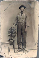 Portrait photograph of farmer posed standing next to chair