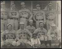 [101 Ranch baseball team, 11 men and 1 boy in front of a building]