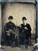 Two men seated with weaponry