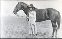 Bonnie McCarroll standing beside unsaddled horse