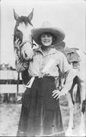 Helen Texas in cloth split riding skirt posed with pinto horse