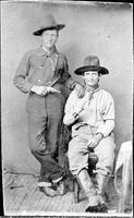 Two cowboys posing with knife and revolver