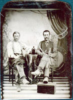Two sitting men in knee high boots with whiskey bottles & knives