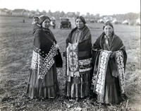 Three Osage Women wearing ribbon blankets with baby