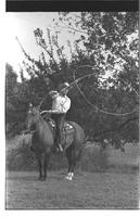 [Junior Eskew, sitting atop horse, spins loop for November 1969 Western Outfitter article]