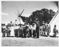 [Line of men & women dressed as cowboys & pioneers]