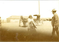 [Indian woman handing something to possible agent with horse and carriage behind]