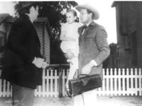 [Brad Dexter talks with Joel McCrea who is holding a little girl in one arm & doctor's bag in other