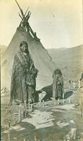 [Southern Ute woman and child tanning hide in front of tipi]