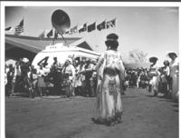 [Indian woman facing audience and television camera and mobile unit- rear view]