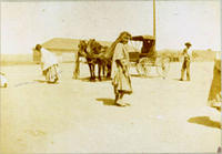 [Indian woman carrying sack of goods with her head, horse team & carriage behind]