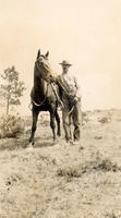 [Unidentified man standing beside saddled horse]