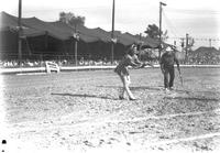 [Unidentified cowboy whipping cork out of bottle held by female assistant]