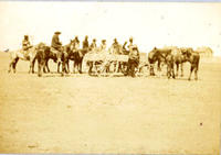 [Nine Indians on horses behind a buckboard wagon with one standing in front]
