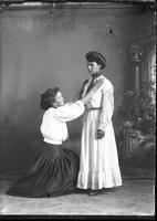 [Single portrait of two Females, one young standing, one adult kneeling]