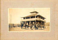 [Five unidentified cowboys on horses in front of house]
