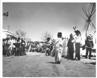 [Indian woman hand talking as spectators look on]