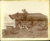 [Hunter's camp with tent, wagon, and antlers]