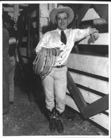 Unidentified cowboy standing with coiled rope