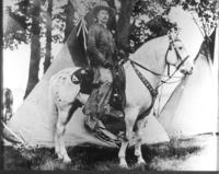 Col. Zack Miller mounted on Ben Hur standing in front of Indian Teepie