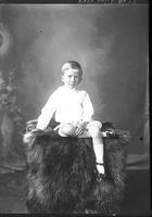 [Single portrait of a young Boy sitting on studio prop]