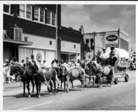[Six-team of ponies pulling small covered wagon, "Frontier City or Bust"]