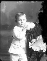 [Carte de Visite single portrait of an young Boy standing & leaning on chair]