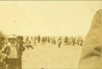 [Indian children in hats & coats in foreground, unidentified social event occurs in background]