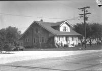 [Long shot of Holze home with family members in front]