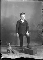 [Single portrait of young Boy wearing a two piece suit & a dog]