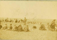 [Indian women sitting on ground in circle with Indian cowboy standing in center, social event]