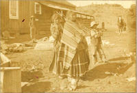 [Indian women standing, waiting amidst a cluttered background]