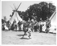 [Pair of male Indian dancers with others & two tipis behind]