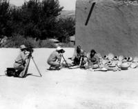 Two men filming Maria and Julian Martinez making pottery