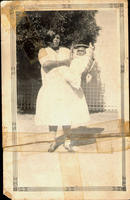 [Native American woman standing & holding cradle with baby]