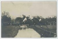 [Horses and riders in steeplechase over water hazard]