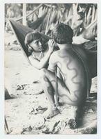 [Native Venezuelan girl painting decorations on a boy]